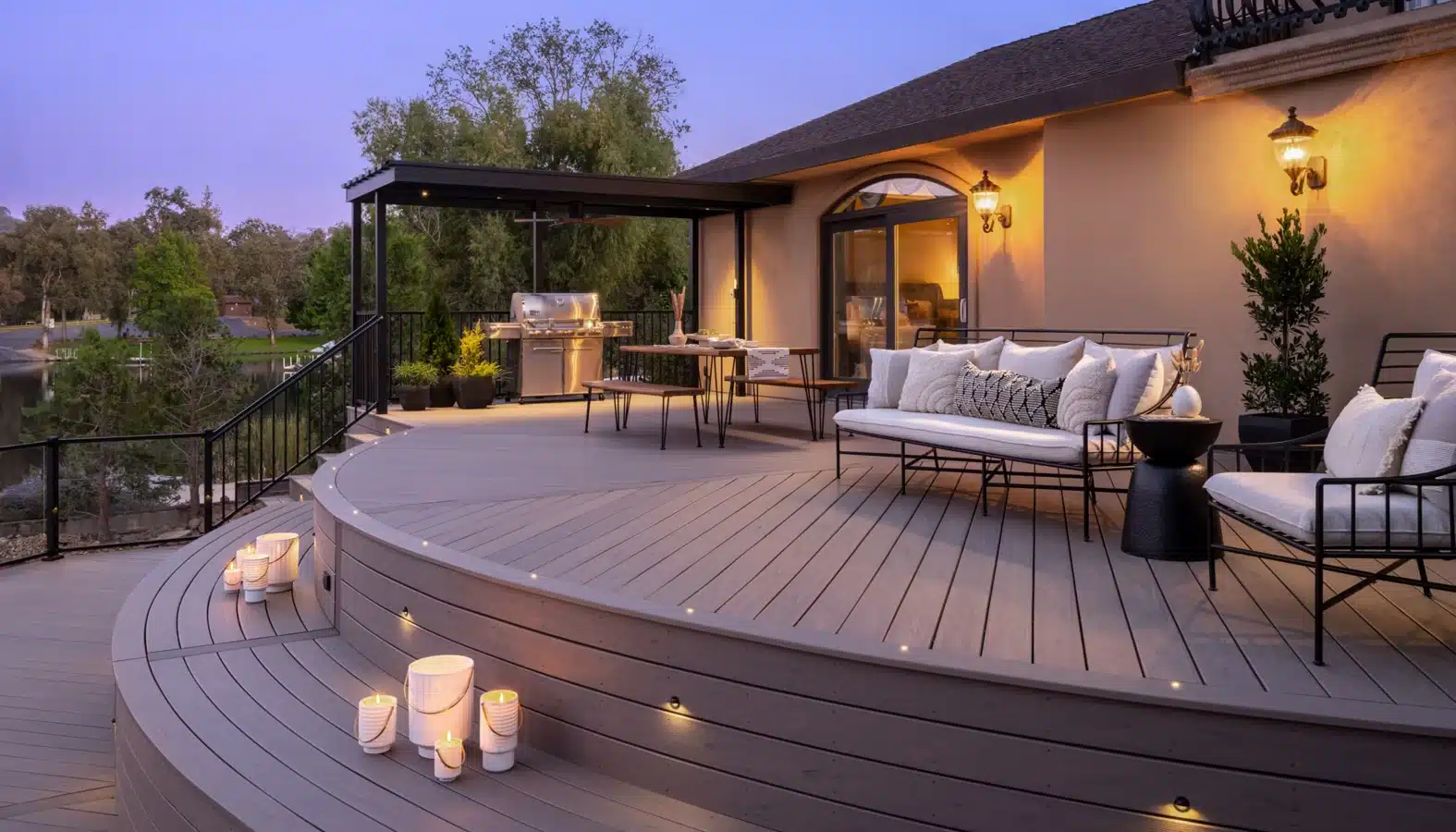A close-up view of a beautifully constructed Trex decking patio, showcasing the rich, textured surface and vibrant colors of the boards. In the foreground, focus on the wood-like appearance of the decking, emphasizing its durability and premium quality. In the middle ground, add a cozy outdoor seating arrangement with professional, modestly dressed individuals discussing home improvement ideas, holding blueprints and samples. In the background, depict a clear blue sky and lush greenery, with a well-manicured lawn and trees framing the area, creating an inviting atmosphere. The sunlight filters through the leaves, casting soft shadows on the decking, capturing a bright and cheerful mood, perfect for illustrating modern outdoor living spaces. Trex deck with lights - cost of trex decking