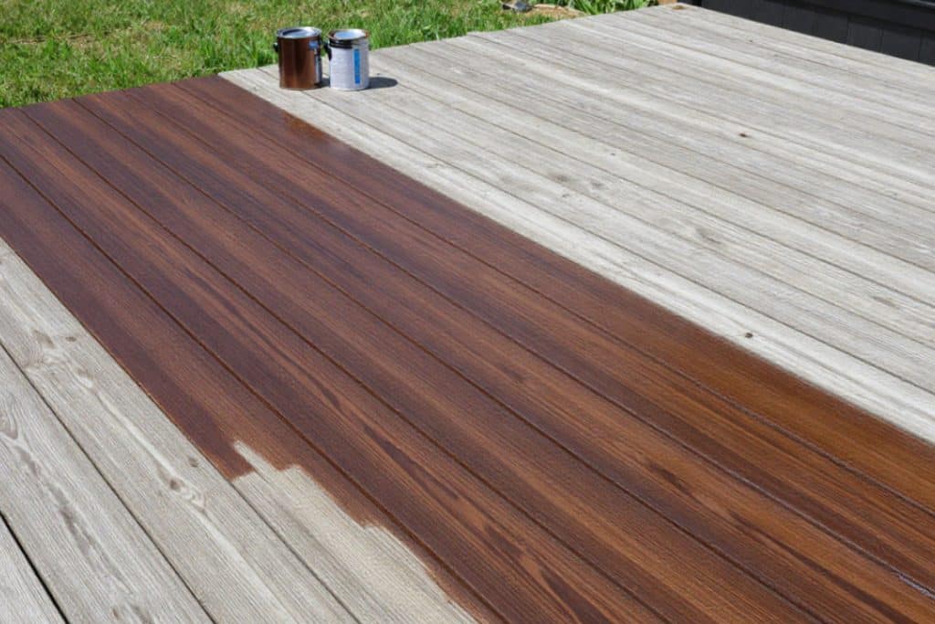 Brush applying deck stain showing proper technique and even coverage