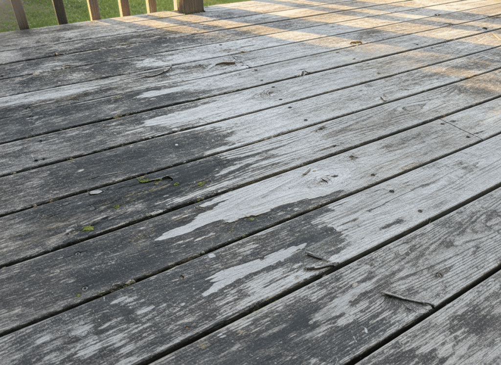Deck showing multiple signs of wear including fading, water stains, and peeling finish