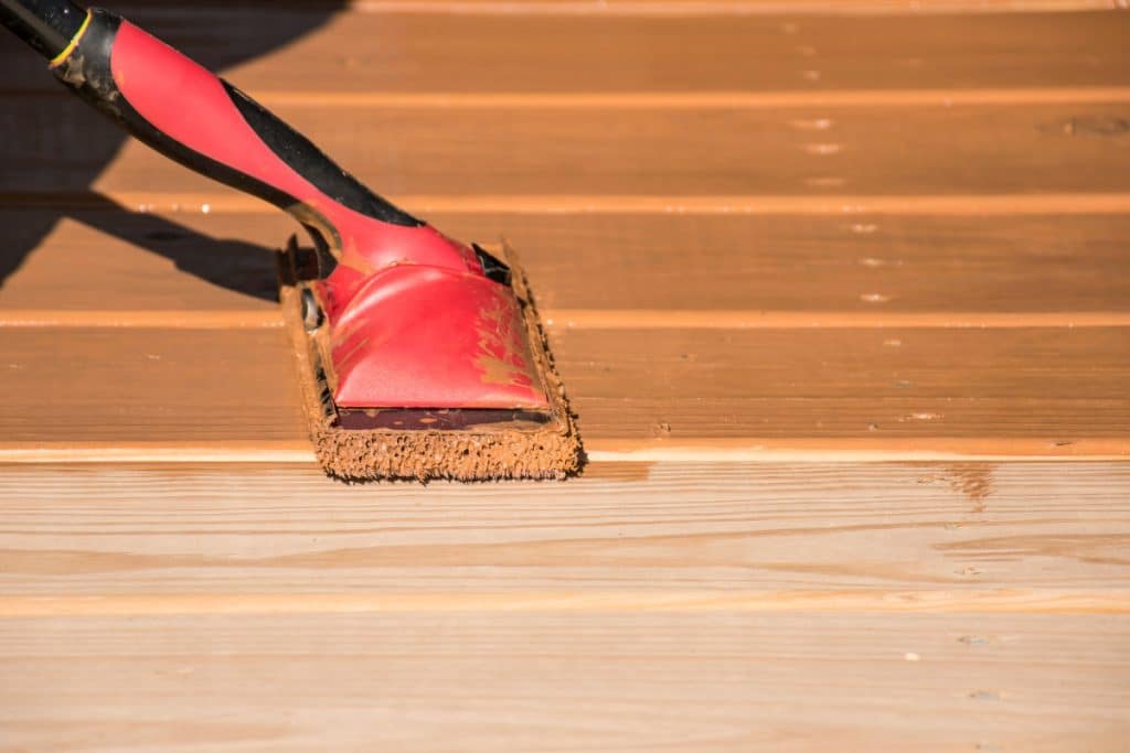 Deck stain remover being applied to strip old failing finish from wood
